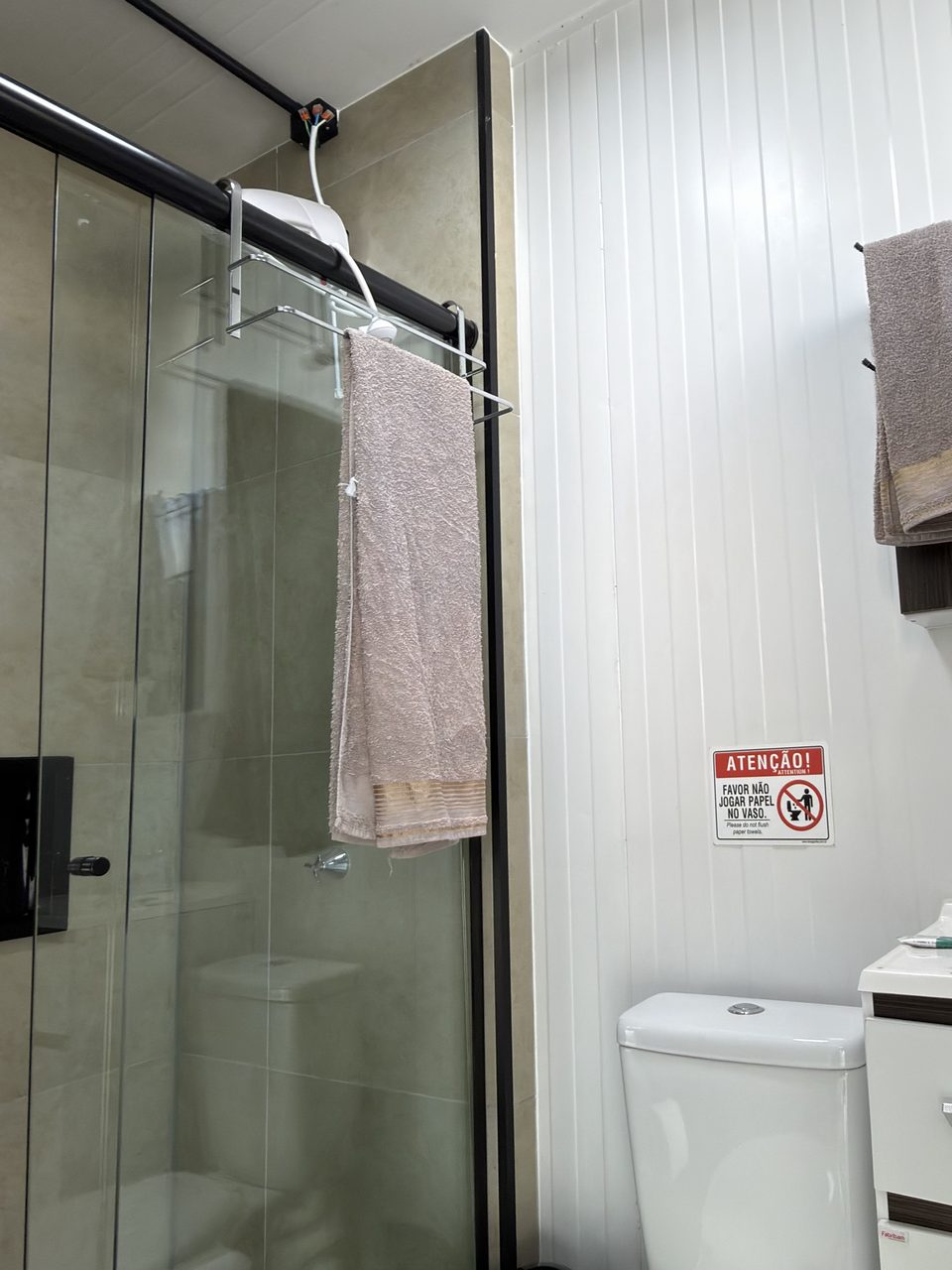 O banheiro do Quarto 5, com box de vidro e armário com espelho.