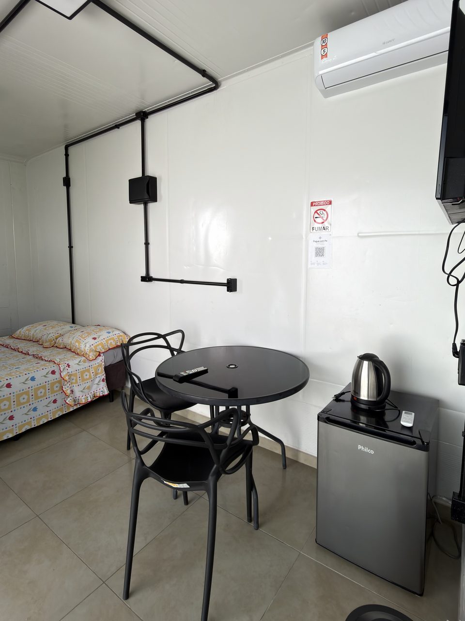 A mesa redonda e o frigobar do Quarto 5.