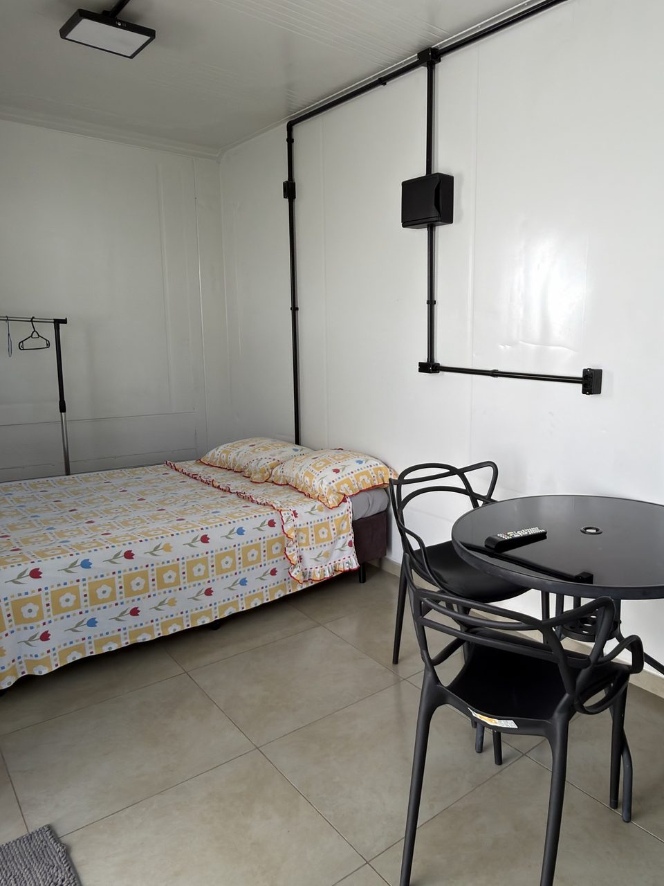 O Quarto 5 por dentro: a cama, a mesa redonda com cadeiras e a chaleira.
