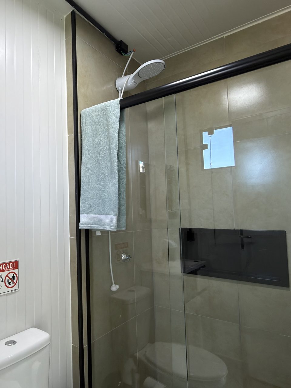 O banheiro do Quarto 6, com box de vidro e chuveiro.