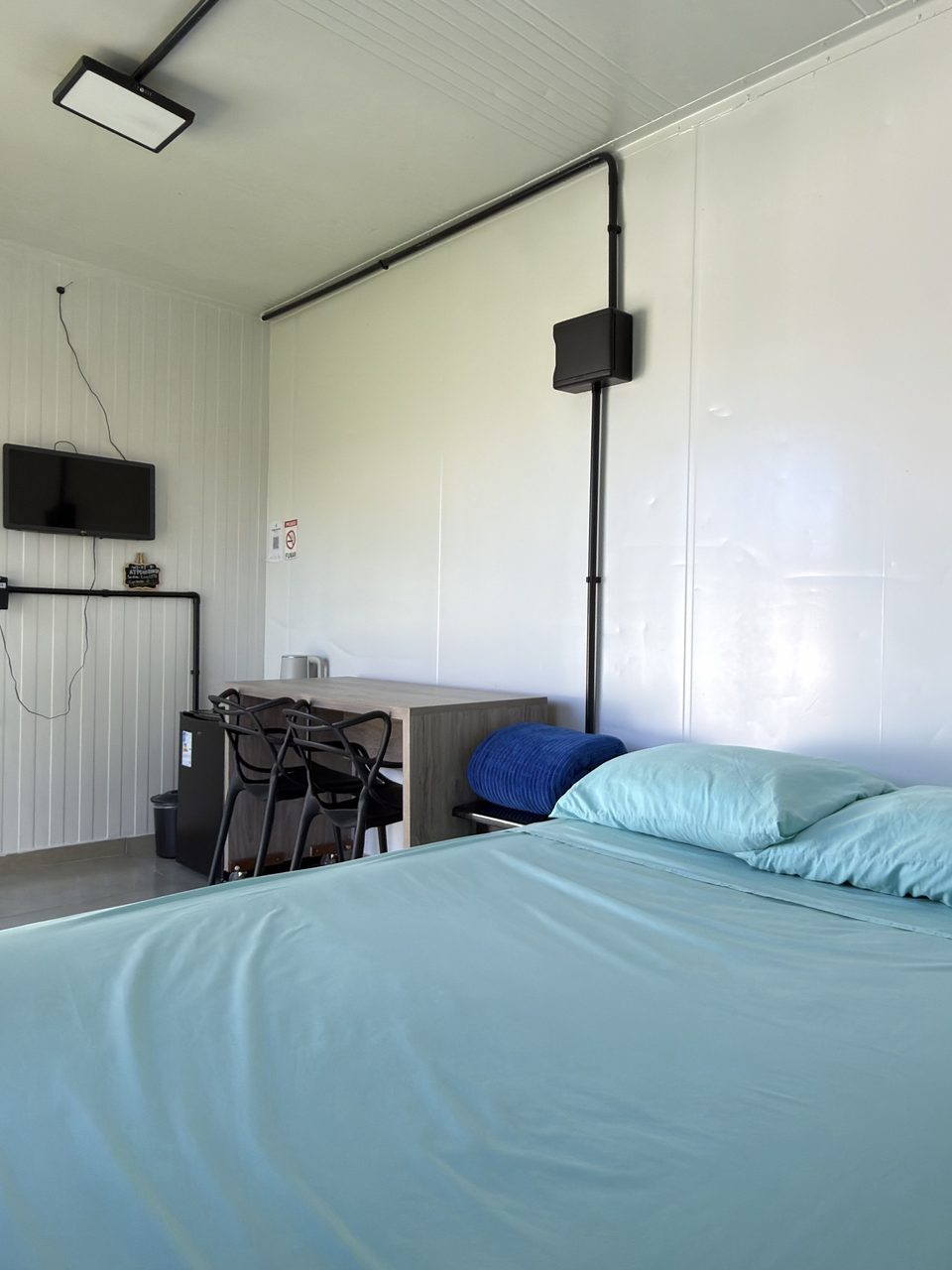 A cama de casal do Quarto 6, com a TV na parede ao fundo.