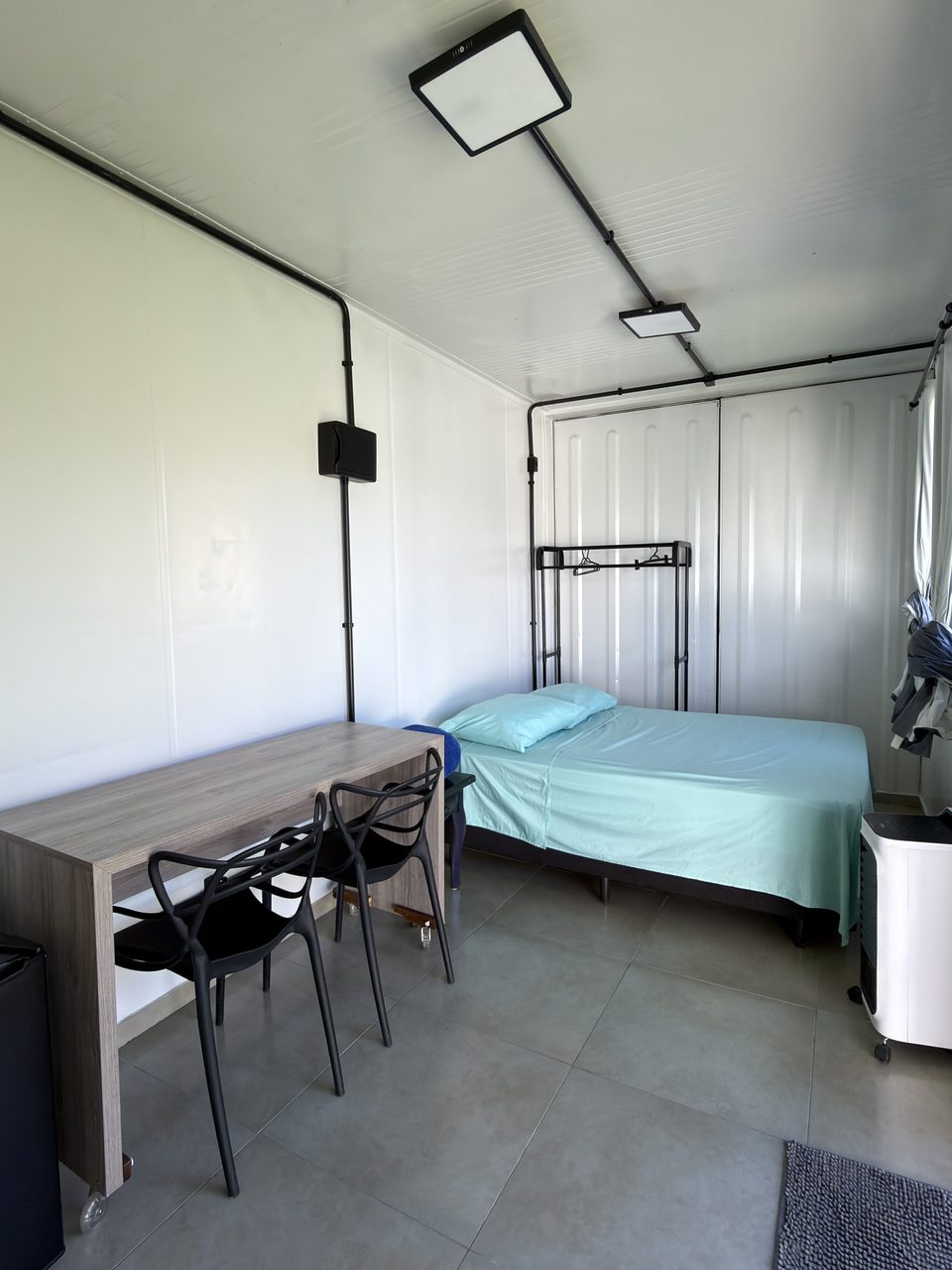 A mesa com duas cadeiras e a cama do Quarto 6.