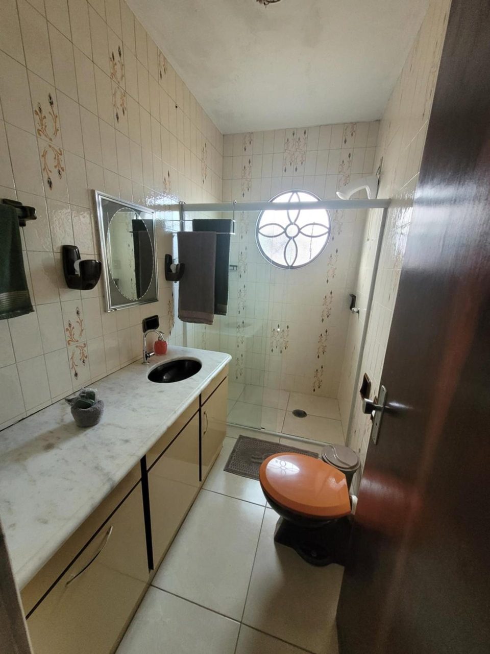 Banheiro de uma suíte da casa, com bancada de mármore e espelho.