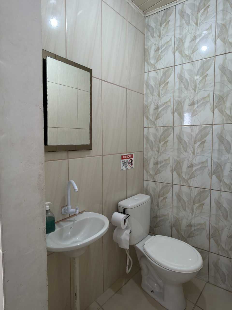 O banheiro do Quarto 2, com pia, espelho e azulejo claro.