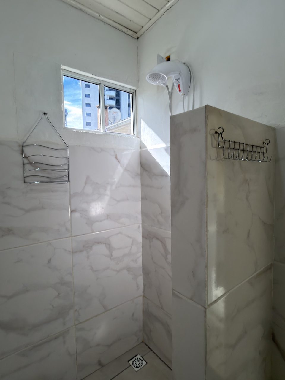 O chuveiro do Quarto 2, no box de alvenaria com janela.