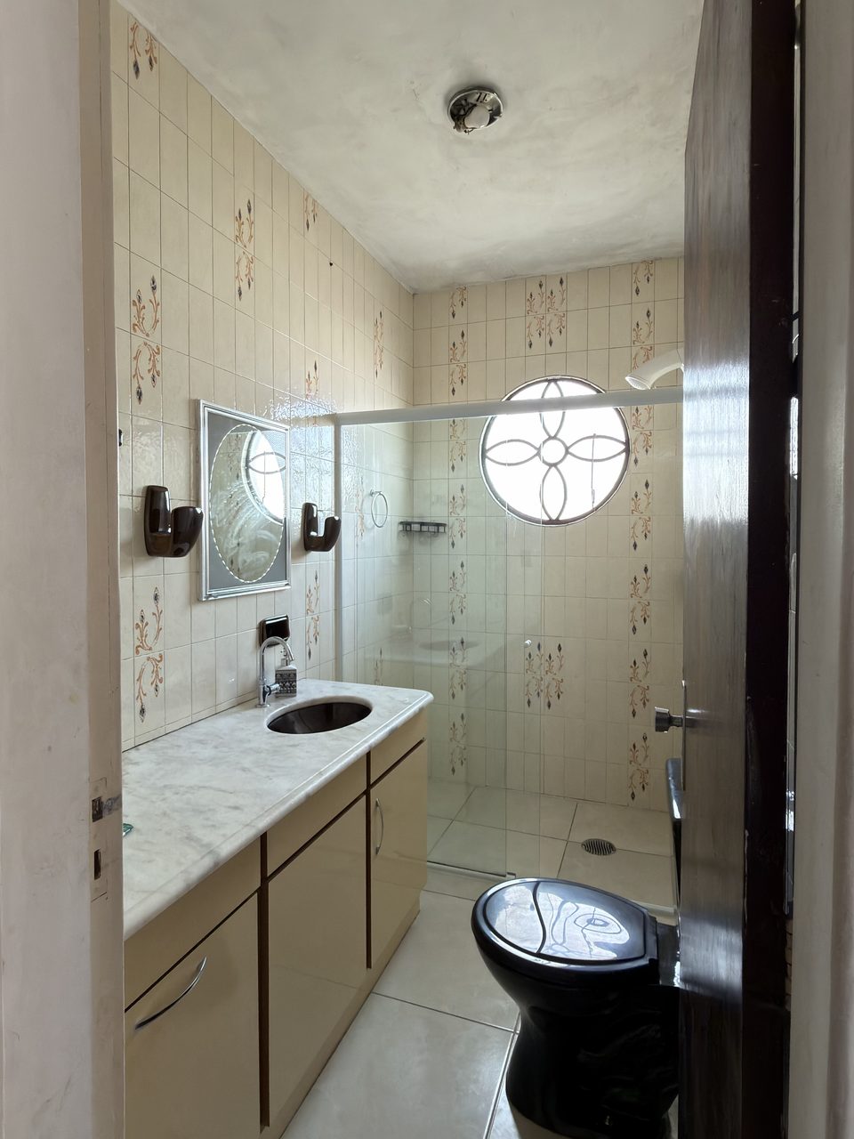 O banheiro do Quarto 3, com box e bancada de armário marrom.